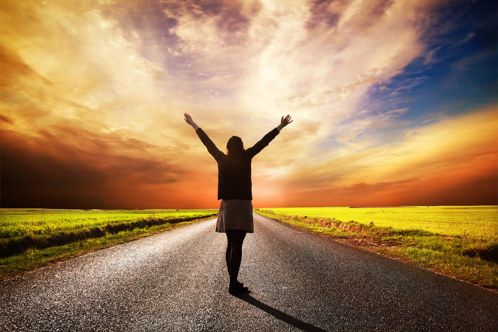 Depression therapist Longmont, Niwot, Frederick, Firestone, Boulder county, Colorado, man breathing exercises, counseling, depression therapy. Happy woman standing with hands up on long straight road facing the sun. Sunset sky
